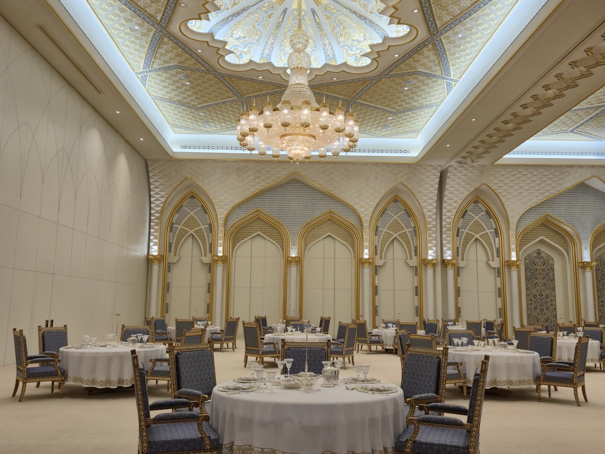 Empty ballroom set with round dinner tables under chandeliers.